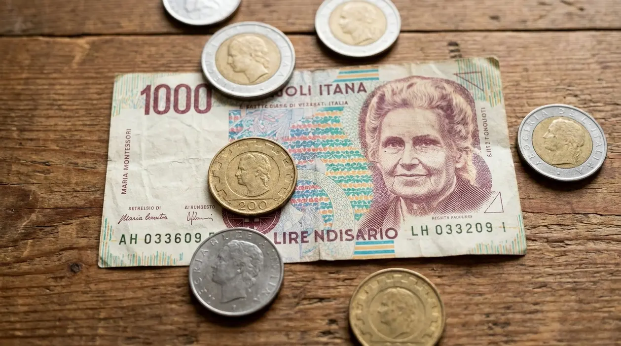 Banconota da 1000 lire con Maria Montessori e monete italiane su un tavolo di legno