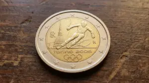 Moneta da 2 euro commemorativa Torino 2006 con sciatore, appoggiata su una superficie di legno