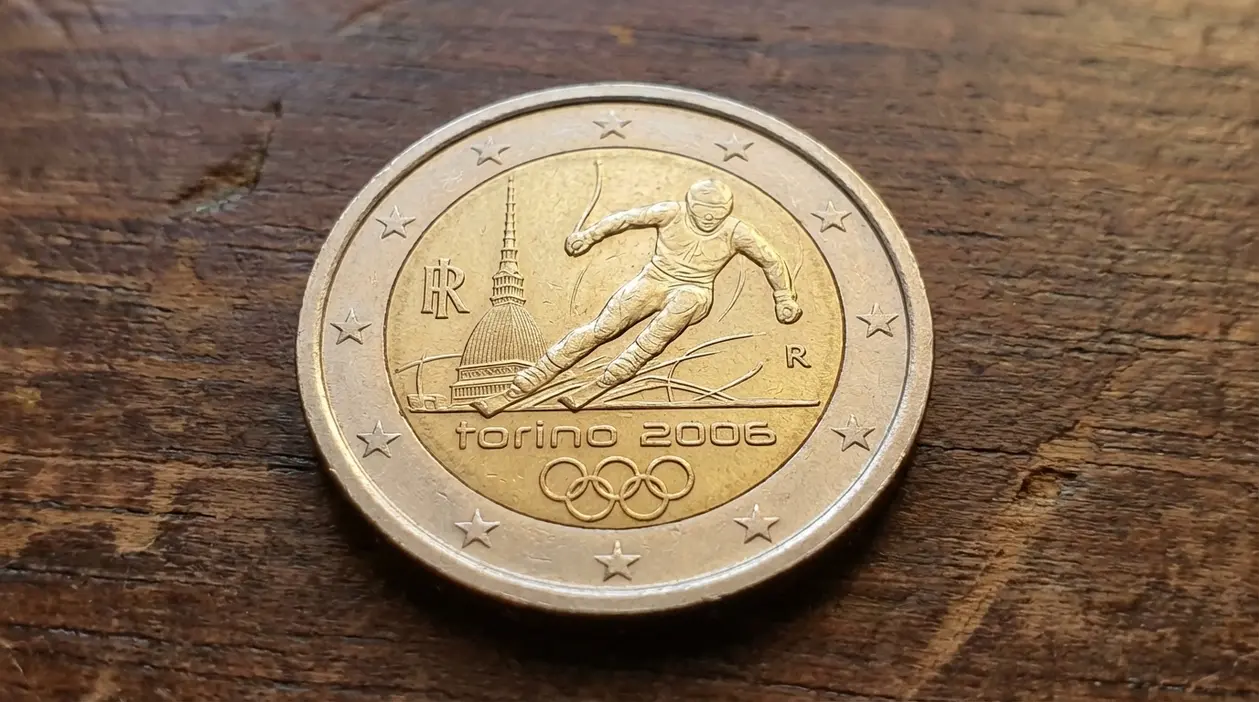 Moneta da 2 euro commemorativa Torino 2006 con sciatore, appoggiata su una superficie di legno