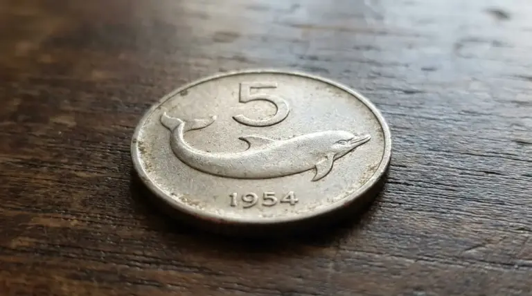 Moneta da 5 lire con delfino del 1954 appoggiata su un tavolo di legno