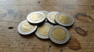 Gruppo di monete italiane da 500 lire bimetalliche appoggiate su un tavolo di legno