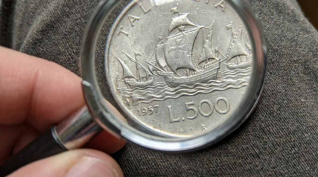 Moneta da 500 lire d'argento con le caravelle e data 1957 osservata con una lente d'ingrandimento
