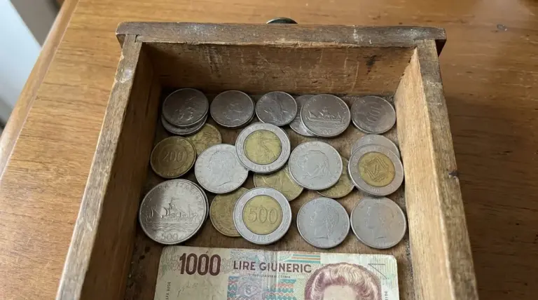 Monete italiane in lire dentro un cassetto di legno, con alcune 500 lire in evidenza