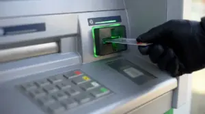 Mano con guanto inserisce una carta nel bancomat, immagine legata al rischio di truffe e furto di dati.