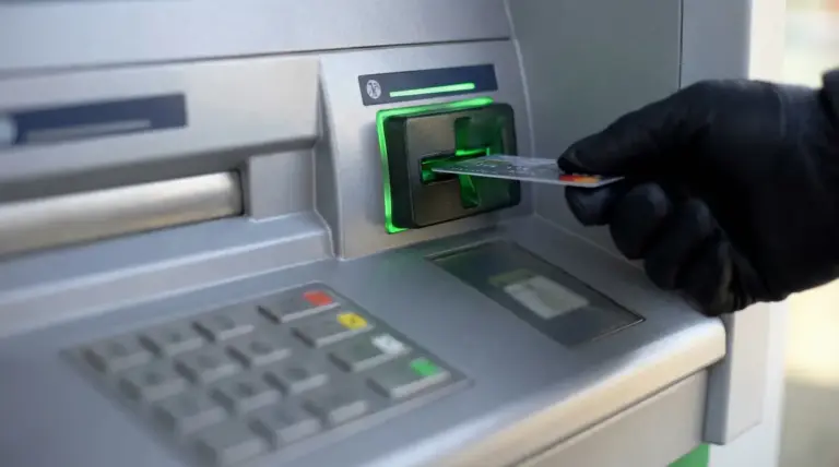 Mano con guanto inserisce una carta nel bancomat, immagine legata al rischio di truffe e furto di dati.