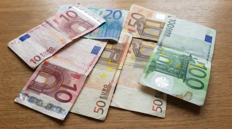 Banconote in euro usurate e spiegazzate appoggiate su un tavolo, tra cui 10, 20, 50 e 100 euro