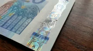 Primo piano di una banconota da 20 euro con banda olografica danneggiata, possibile segno di manomissione