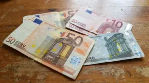 Banconote in euro da 5, 10 e 50 appoggiate su un tavolo di legno