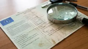 Carta di circolazione italiana su un tavolo con lente d’ingrandimento, simbolo da controllare per evitare multe