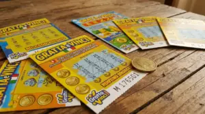 Biglietti Gratta e Vinci sparsi su un tavolo di legno con una moneta accanto