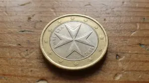 Moneta da 1 euro di Malta con croce a otto punte appoggiata su una superficie in legno