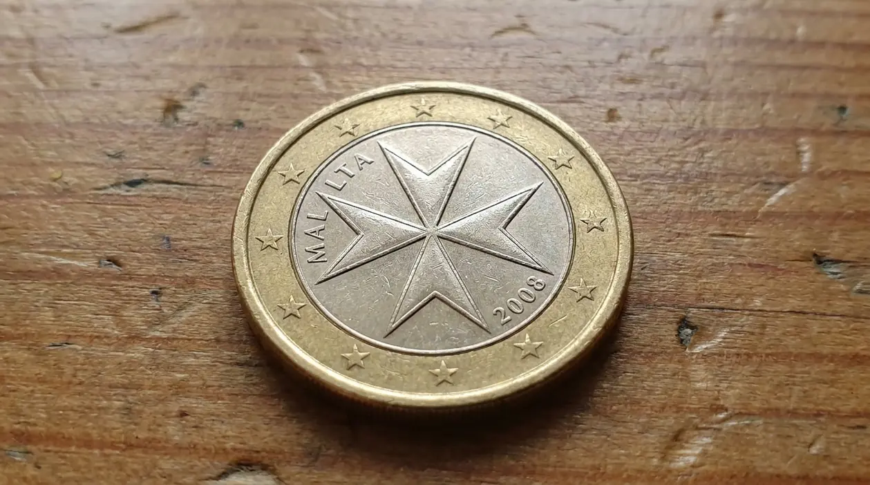 Moneta da 1 euro di Malta con croce a otto punte appoggiata su una superficie in legno