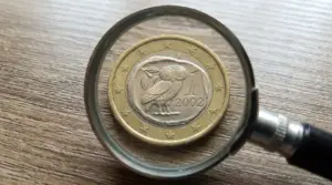 Moneta da 1 euro vista con una lente d’ingrandimento su un tavolo, tema numismatica e valore raro