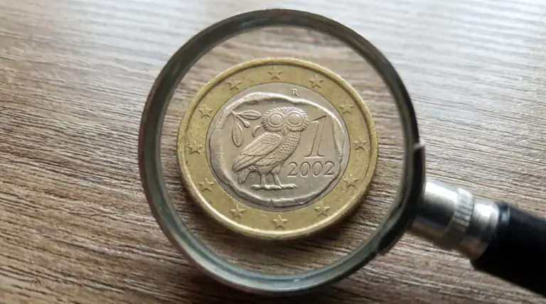 Moneta da 1 euro vista con una lente d’ingrandimento su un tavolo, tema numismatica e valore raro