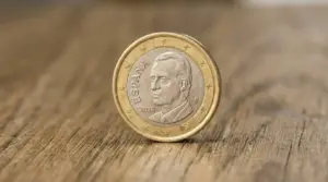 Moneta da 1 euro spagnola con volto maschile appoggiata su una superficie di legno