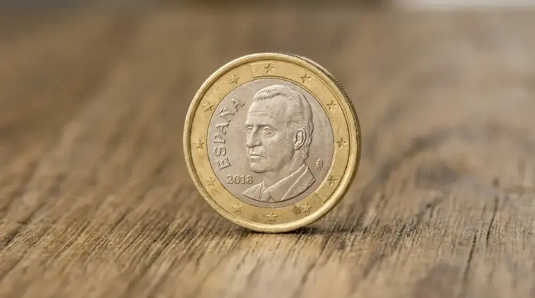 Moneta da 1 euro spagnola con volto maschile appoggiata su una superficie di legno