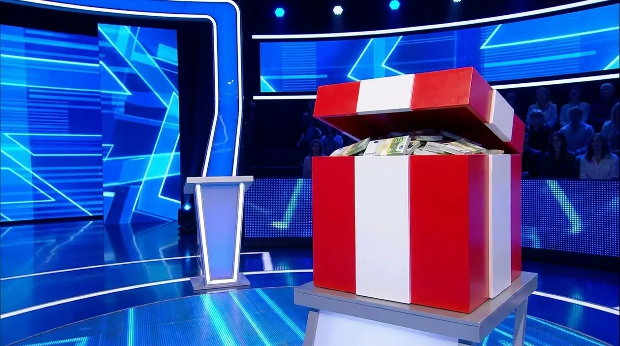 Pacco rosso e bianco aperto con denaro su un set televisivo, simbolo dei premi nei game show