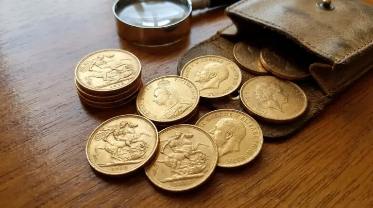 Sterline d’oro sparse su un tavolo accanto a una lente d’ingrandimento e a un portamonete in pelle